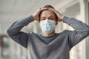 A man with a face mask holding his head because he's stressed out because of having to move out of his LA music studio due to coronavirus.