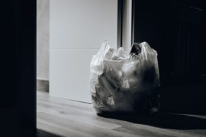 Garbage in a plastic bag next to a door.