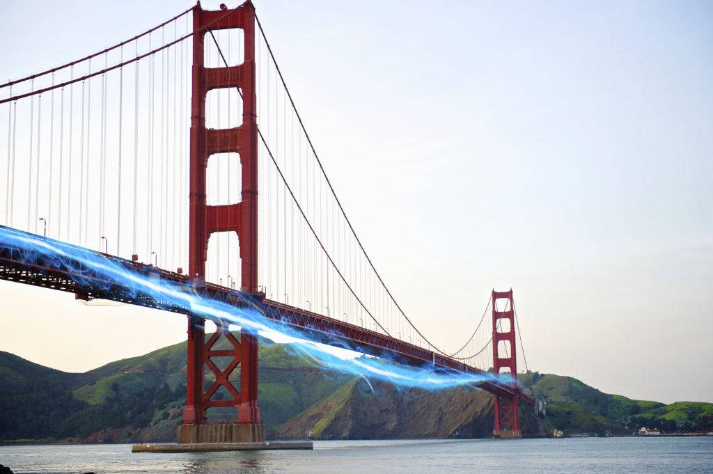 Blue streak of light passing by Golden Gate Bridge against clear sky